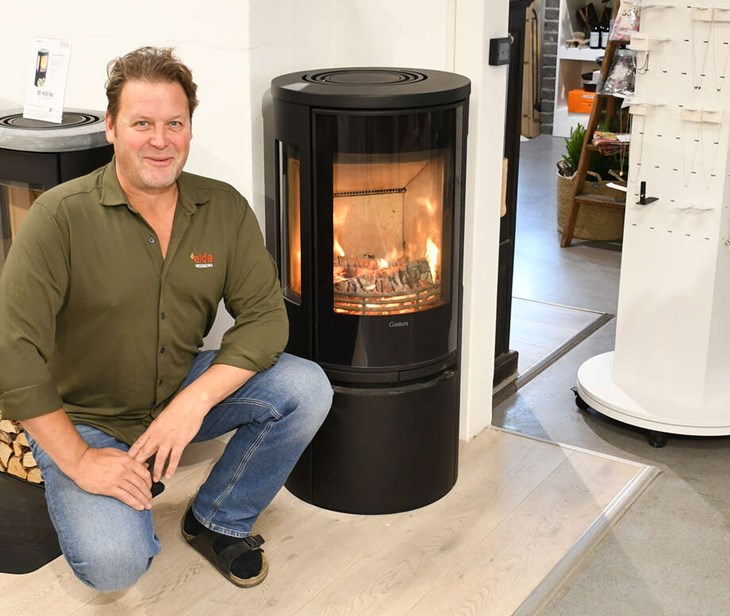 Henrik intill en kamin som saknar reglage. Istället är kaminen utrustad med givare som talar om hur mycket luft som skall tillföras. Foto: Jens Wikholm