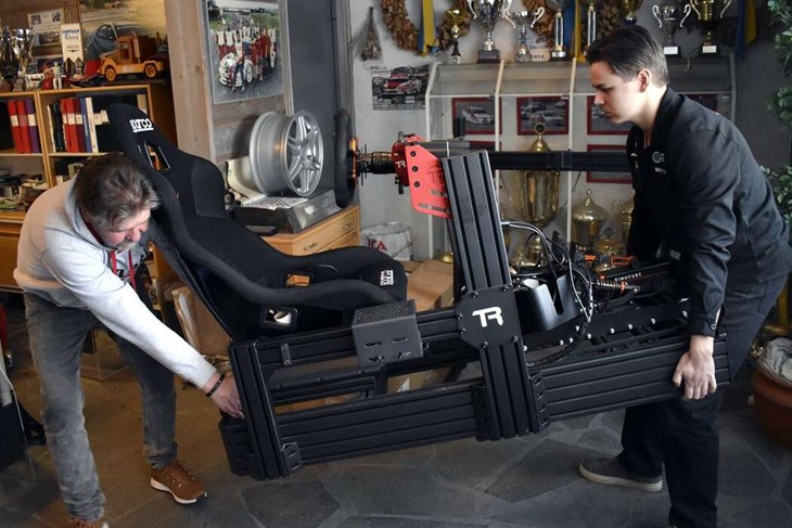 Tomas och Jonathan Engström hjälps åt att flytta den sistnämndes simulator inför fotograferingen. Tack vare simulatorn kan Jonathan provköra banor från hela världen, hemifrån Säter. "Sådant här fanns inte på min tid, då fick man vackert gå banan till fots för att lära sig den", muttrar Tomas, med glimten i ögat. Foto: Pär Sönnert