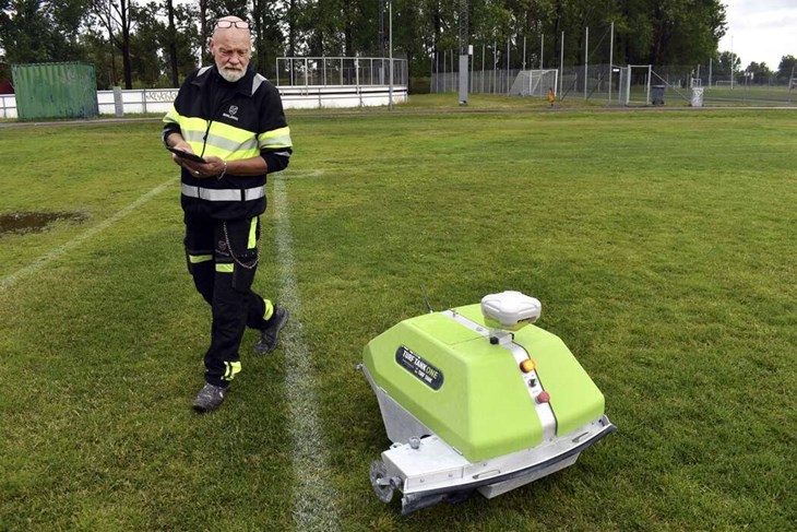 Magnus Lindberg är gruppledare för vaktmästarna inom ”Idrottsenheten norra” i  Borlänge kommun. Här demonstrerar han hur, den ännu namnlösa, linjeringsroboten rör sig. Inför Dalecarlia Cup, som hålls nästa vecka, ska roboten linjera alla fotbollsplaner vid Sportfältet. Foto: Pär Sönnert