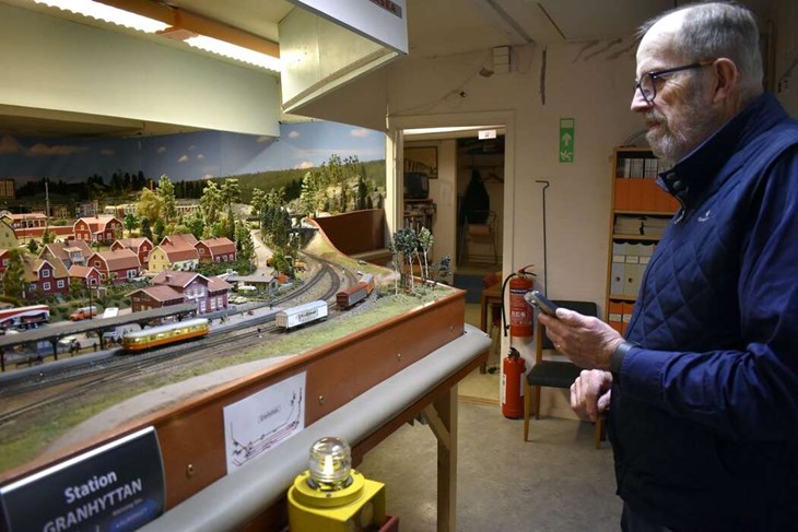 Med hjälp av en app i sin telefon kan Magnus Bohlin styra en av rälsbussarna. Den tuffar i gång längs banan och Magnus kan även spela upp tågljud och inspelade stationsutrop. "Men jag åkte ifrån min andra telefon, som jag kan styra ångloket med, så ångloket får stå stilla i dag", säger han. Foto: Pär Sönnert