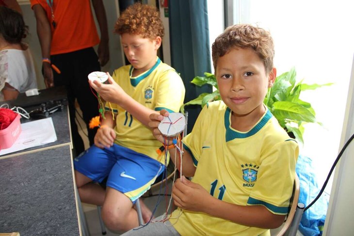 Santi och Amado tvinnade garntrådar i ett specellt mönster på en pappskiva, för att skapa en snodd som skulle bli egna armband.