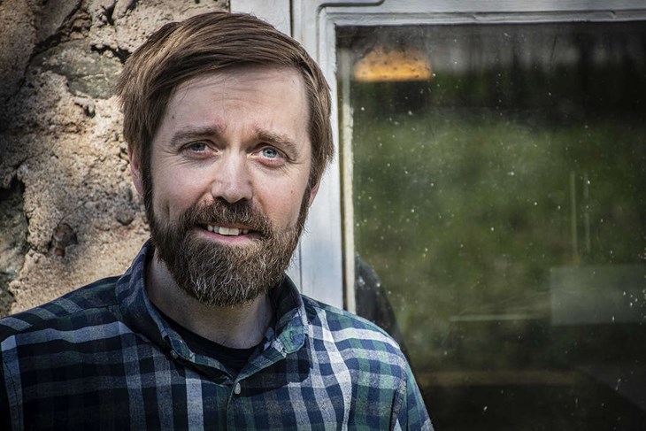 Daniel Kåks (V) pekar på partiets tidning som når alla hushåll. Foto: Christian Larsen