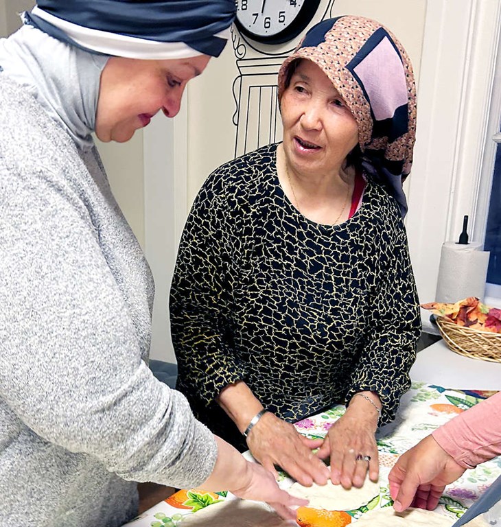 Huda och Fatima har inte samma modersmål men samma kunskap om hur brödet ska hanteras för att bli tunt och fint – utan kavel. Foto: Karin Diffner
