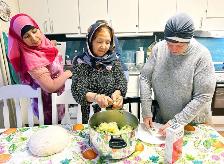 Khadija kontrollerar så alla har en uppgift medan Fatima och Huda hjälps åt att finfördela vitlöken som ska i grönsaksfyllningen. Foto: Karin Diffner